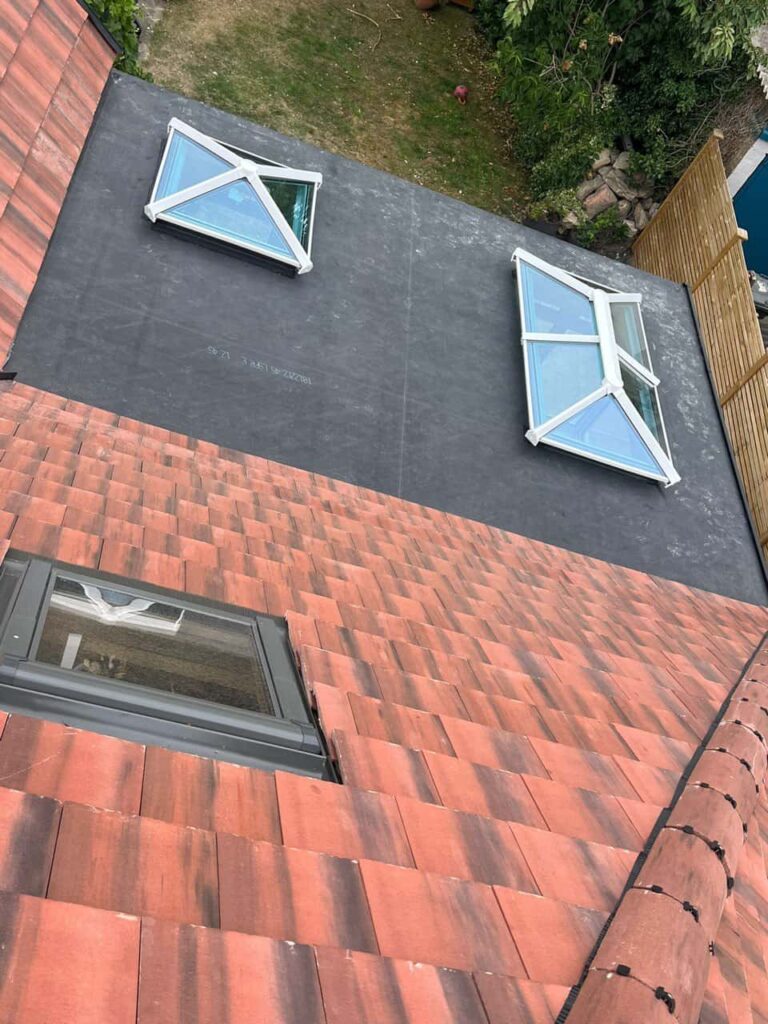 This is a photo taken from the roof ridge looking down a tiled pitched roof on to a flat roof. Works carried out by Aldridge Roofing Repairs